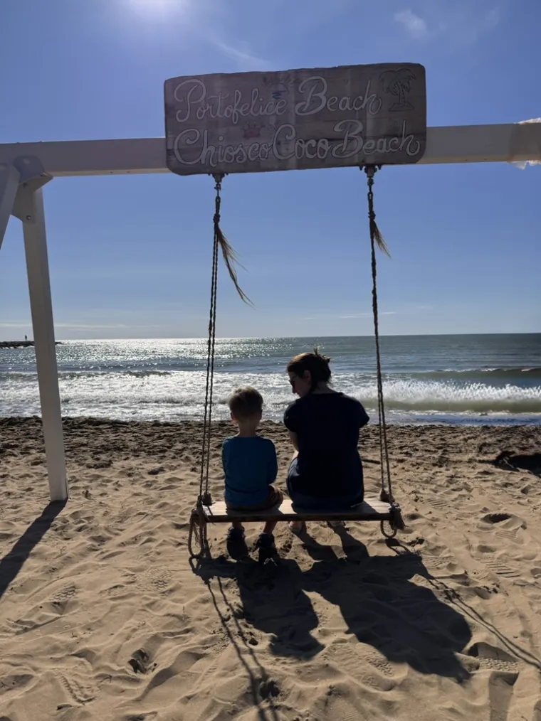 Wir am Strand: auf einer Holzschaukel sitzend, mit Blick aufs Meer.